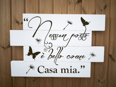 Pannello decorativo in legno stile shabby chic con la frase "Nessun posto è bello come casa mia", su sfondo bianco e sagome di farfalle.
