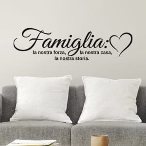 Adesivo murale in vinile nero con citazione sulla famiglia, applicato su una parete chiara sopra il divano del soggiorno.
