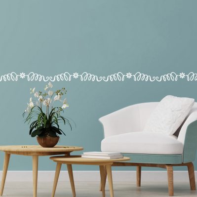 Greca decorativa adesiva da muro bianca applicata su parete azzurro pastello con arredamento minimal.