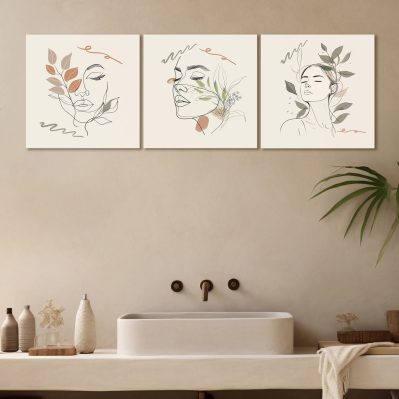 Composizione di tre quadri moderni bagno beauty con volti femminili stilizzati, appesi sopra il lavabo in un ambiente minimal ed elegante.